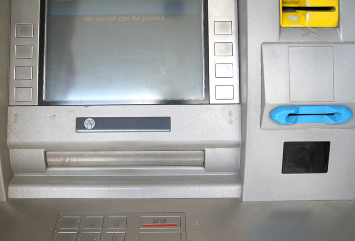 A yellow plastic device on an ATM containing a skimmer