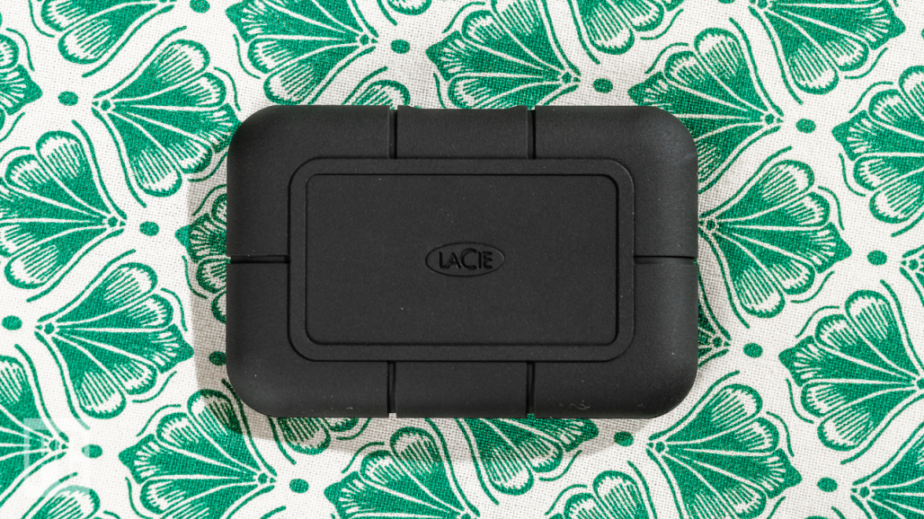 A LaCie Rugged SSD Pro external hard drive sitting on a patterned green and white cloth back drop