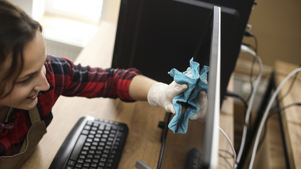 woman wiping down desktop monitor