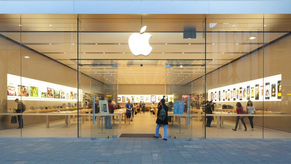 Apple Store exterior with people inside and one person walking in